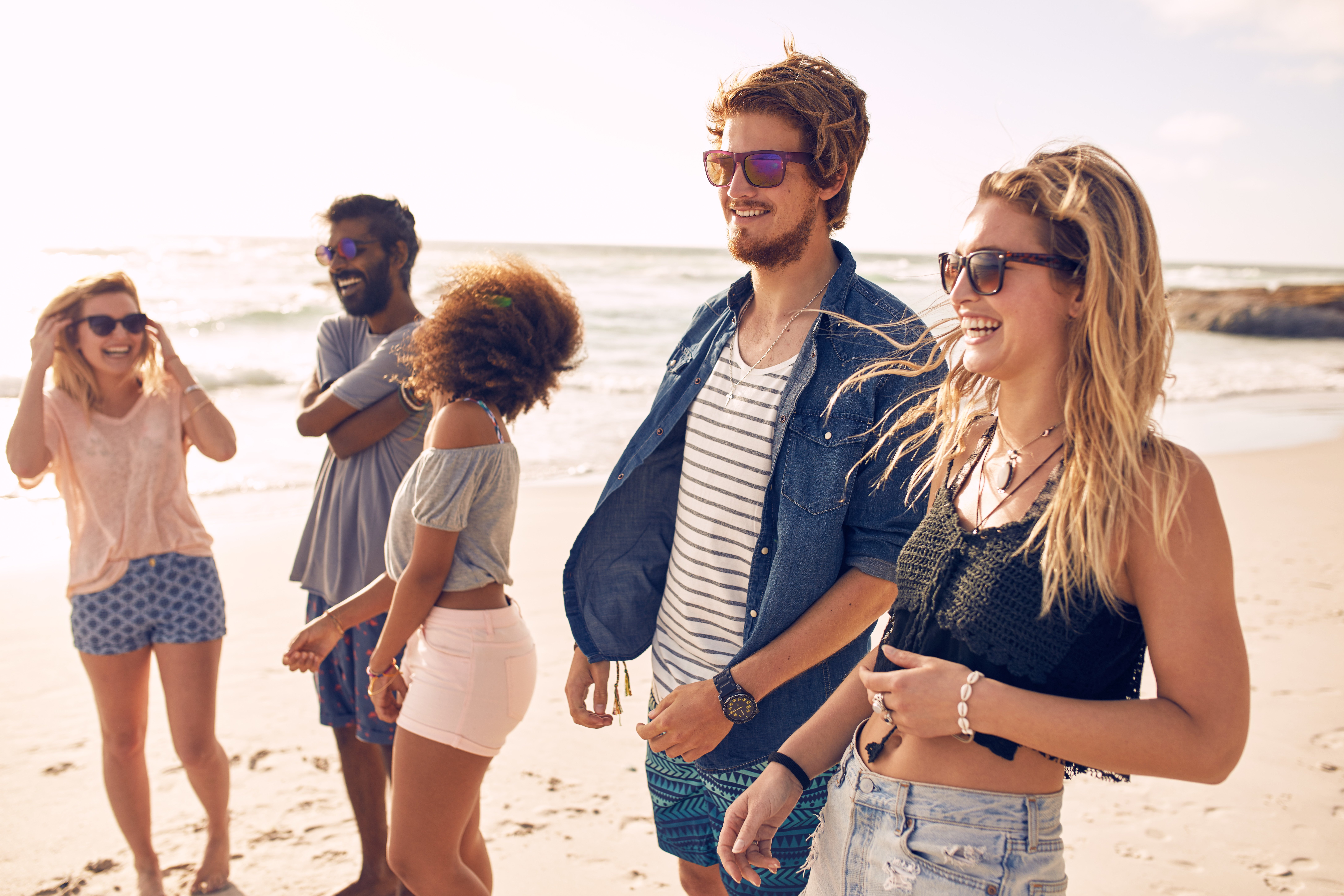 Group of friends walking along a beach at summertime